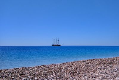 Sailboat sailing on sea against clear blue sky