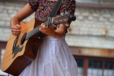 Midsection of woman playing guitar