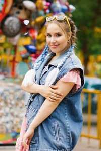 Young woman with blue pigtails in a denim vest in an amusement park