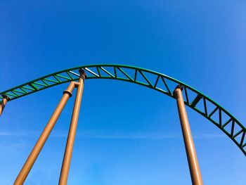 Low angle view of rollercoaster against clear blue sky