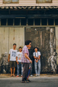 Full length of friends standing against built structure