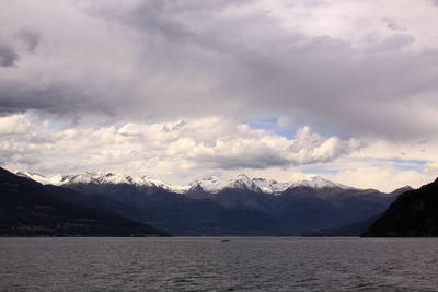 Scenic view of sea and mountains against cloudy sky