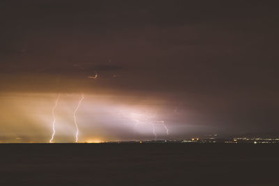 Lightning over sea against sky at night