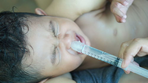 Cropped hand of doctor injecting baby boy nose