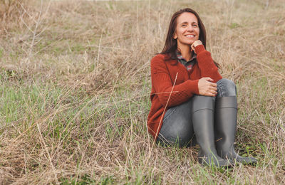 Smiling young woman sitting on field