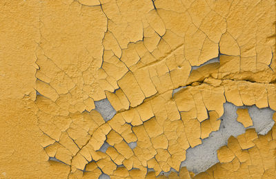 Cracked yellow paint on an old cement wall. the old background is painted yellow on the walls.