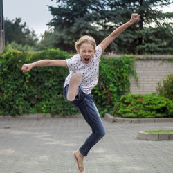 Full length of girl jumping against trees