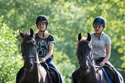 Teenagers riding horse against trees