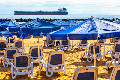 Relaxing beach scene with colorful umbrellas and comfy chairs. large ship view from the beach