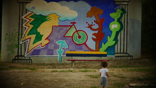 Rear view of boy standing against multi colored wall