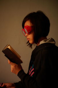 Woman wearing novelty glasses while reading book at home