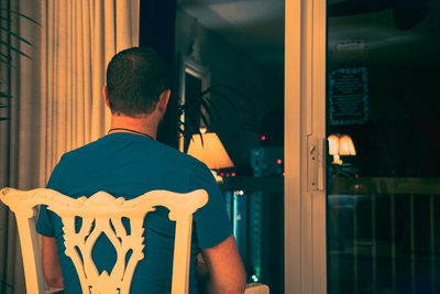 Rear view of man sitting on chair