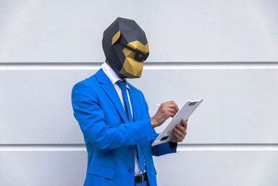 Man holding smart phone while standing against wall