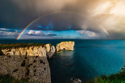 Scenic view of rainbow over sea against sky