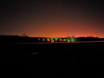 Illuminated field against sky at night