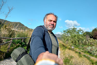 Follow me. man holds and pulls the photographer's hand while walking on rural road.