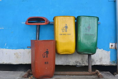 Close-up of garbage bin by wall outdoors