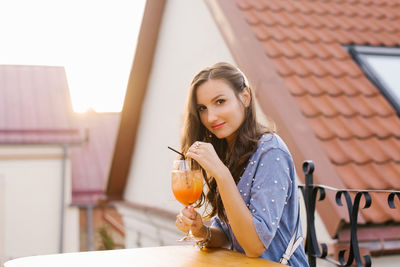 Cheerful young girl is sitting in a cafe and drinking a delicious cocktail