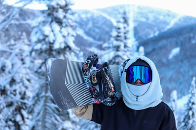 Rear view of woman wearing warm clothing standing against snowcapped mountain