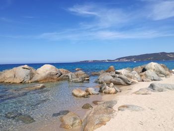 Rocks on beach against blue sky