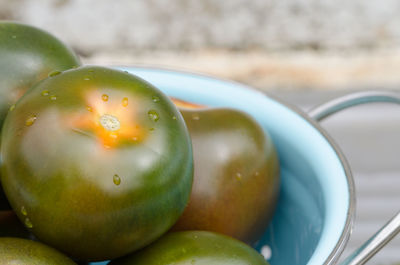 Close-up of unripe tomatoes in colander on table