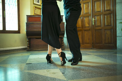 Low section of couple dancing on tiled floor