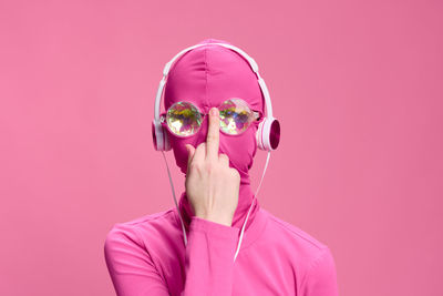 Young woman wearing sunglasses against pink background