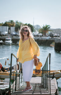 Full length of woman standing on jetty by river against sky