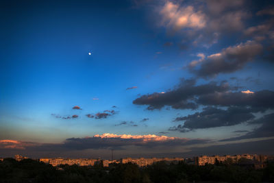 Illuminated cityscape against blue sky at dusk