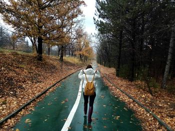 Rear view of woman walking on road during autumn