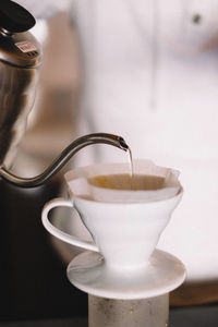 Close-up of kettle pouring water in cup