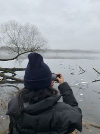 Rear view of man standing by lake