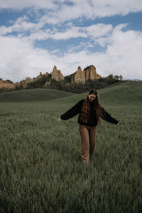 Rear view of woman standing on field against sky