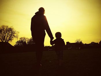Silhouette people on field at sunset