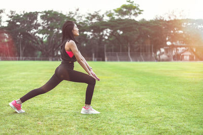 Full length side view of young woman sitting on field