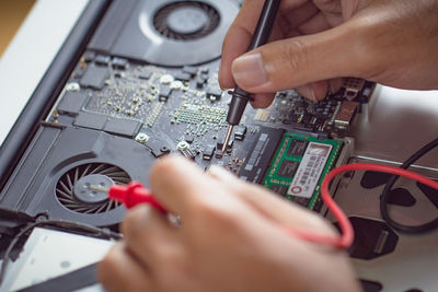 Cropped hands of engineering repairing laptop