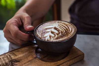 Cropped hand of person holding coffee on table