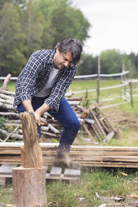 Mid adult man cutting firewood at yard