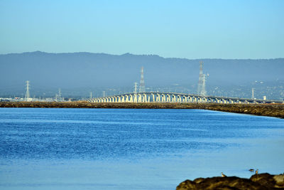 Bridge over river against clear blue sky