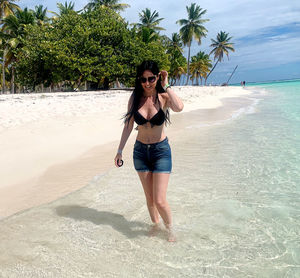 Full length of young woman standing at a paradisiac beach 