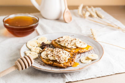 Ready to eat sandwiches with honey, banana and chocolate on a plate on the table. 