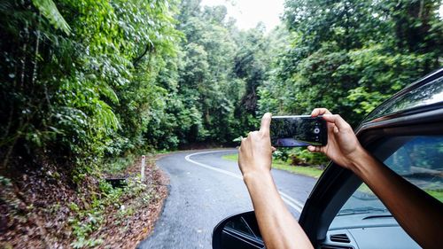 Cropped hands photographing road using smart phone