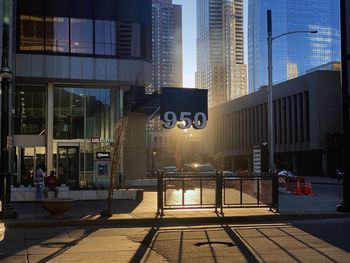 Modern buildings by street against sky in city