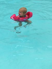 High angle view of girl wearing water wings while swimming in pool