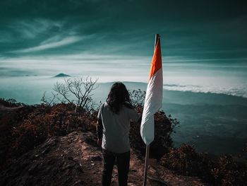 Rear view of woman standing by mountain against sky