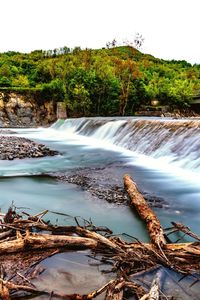 Scenic view of waterfall in forest against sky