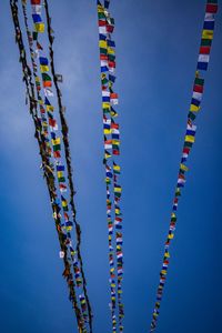 Low angle view of multi colored flags hanging against blue sky