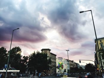 Low angle view of city street against cloudy sky