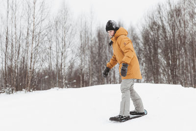 Cute teenage girl rides a snowskate in a winter park, healthy lifestyle