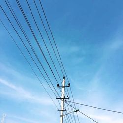 Low angle view of electricity pylon against blue sky